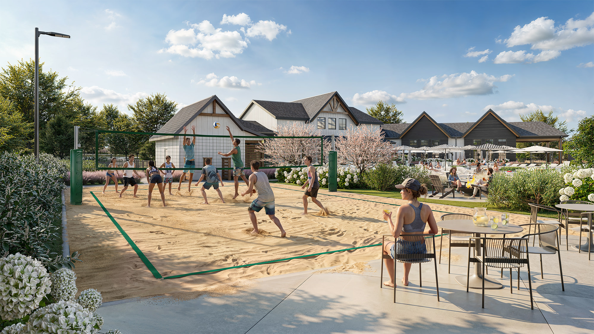 Chandelier Student Living Apartments People play volleyball on an outdoor sand court near a cafe patio with tables and blooming trees under a sunny sky.