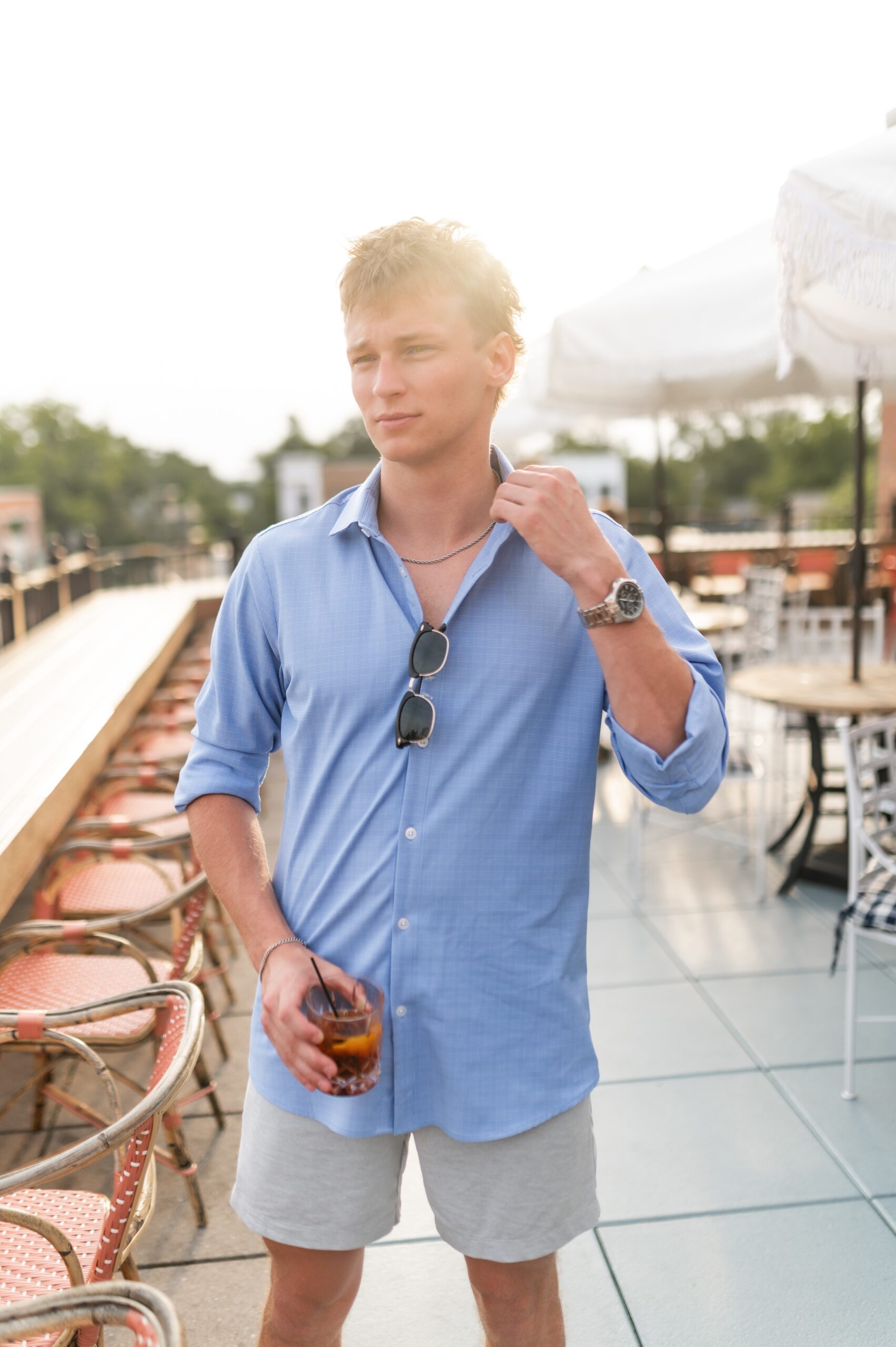 young man holding drink on patio scaled
