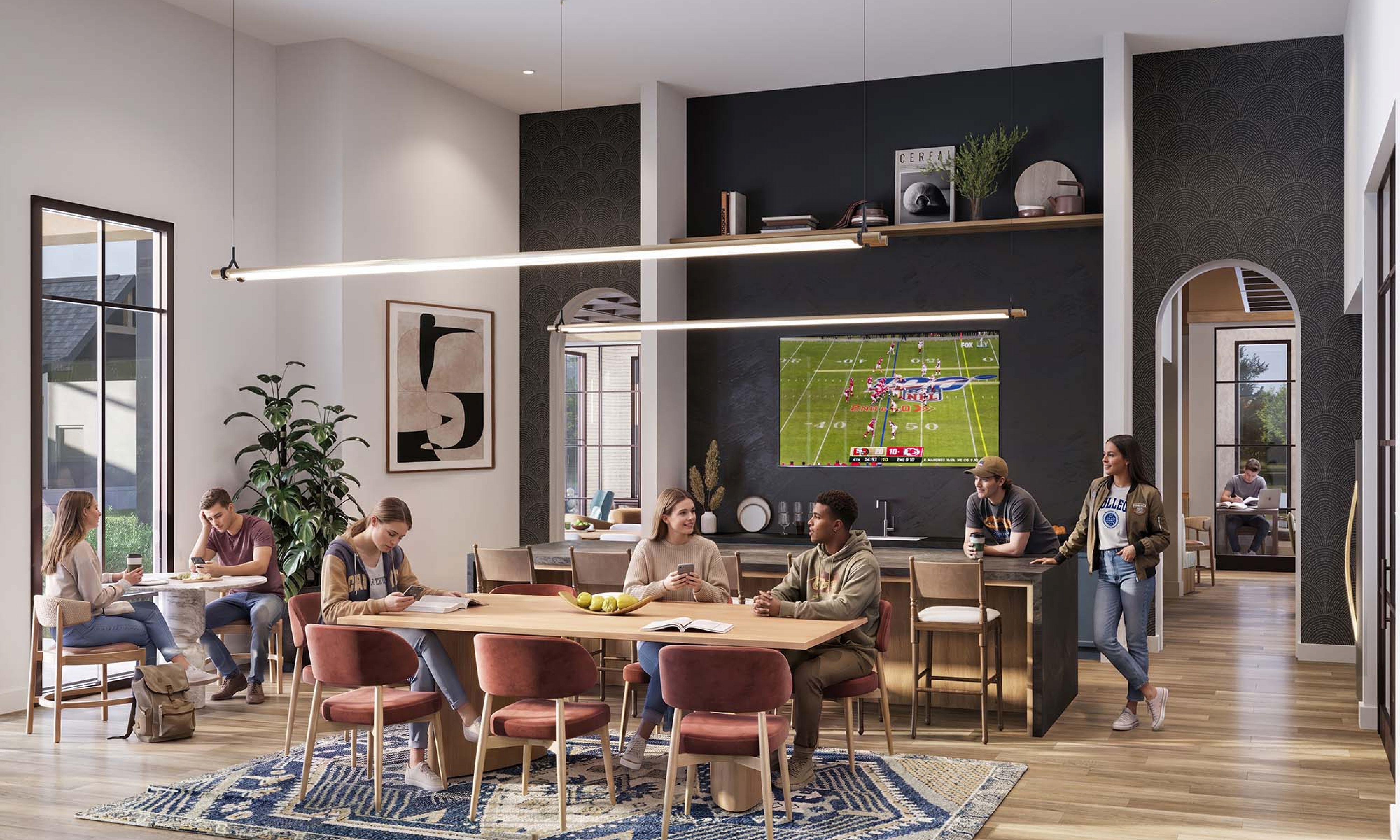 Chandelier Student Living Apartments A group of people socialize and watch football in a modern, stylish kitchen and dining area with large windows and contemporary decor.
